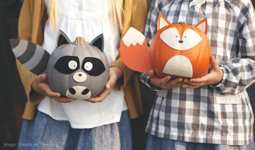 2 girls holding no carve pumpkins: raccoon and fox