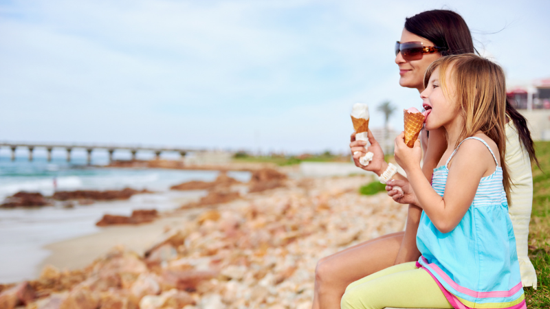 mom and daughter eating ice cream looking off at ocean
