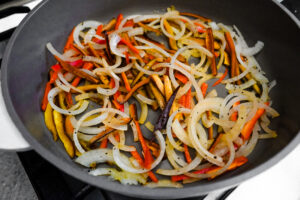 peppers and onions cooking in frying pan