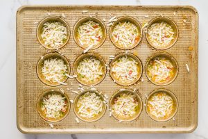 egg mixture with cheese on top in muffin tin
