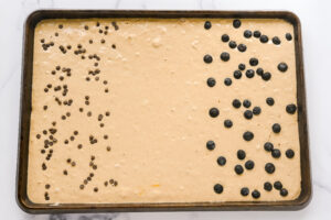 pancake batter on sheet pan with chocolate chips on one side, and blueberries on the other