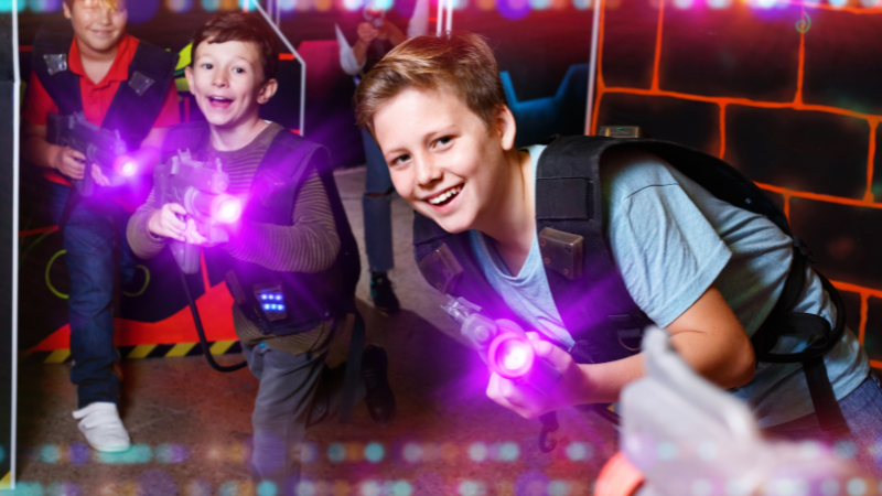 tween boy playing laser tag with 2 friends